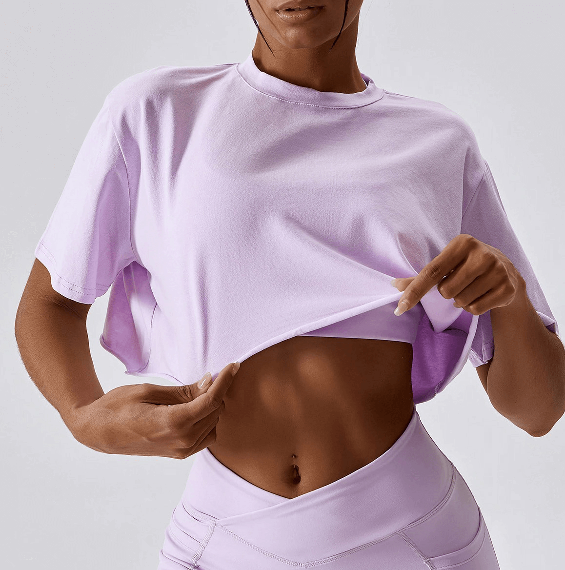 Woman wearing a lavender sports loose crop top showing its fit, ideal for yoga, running, and training.